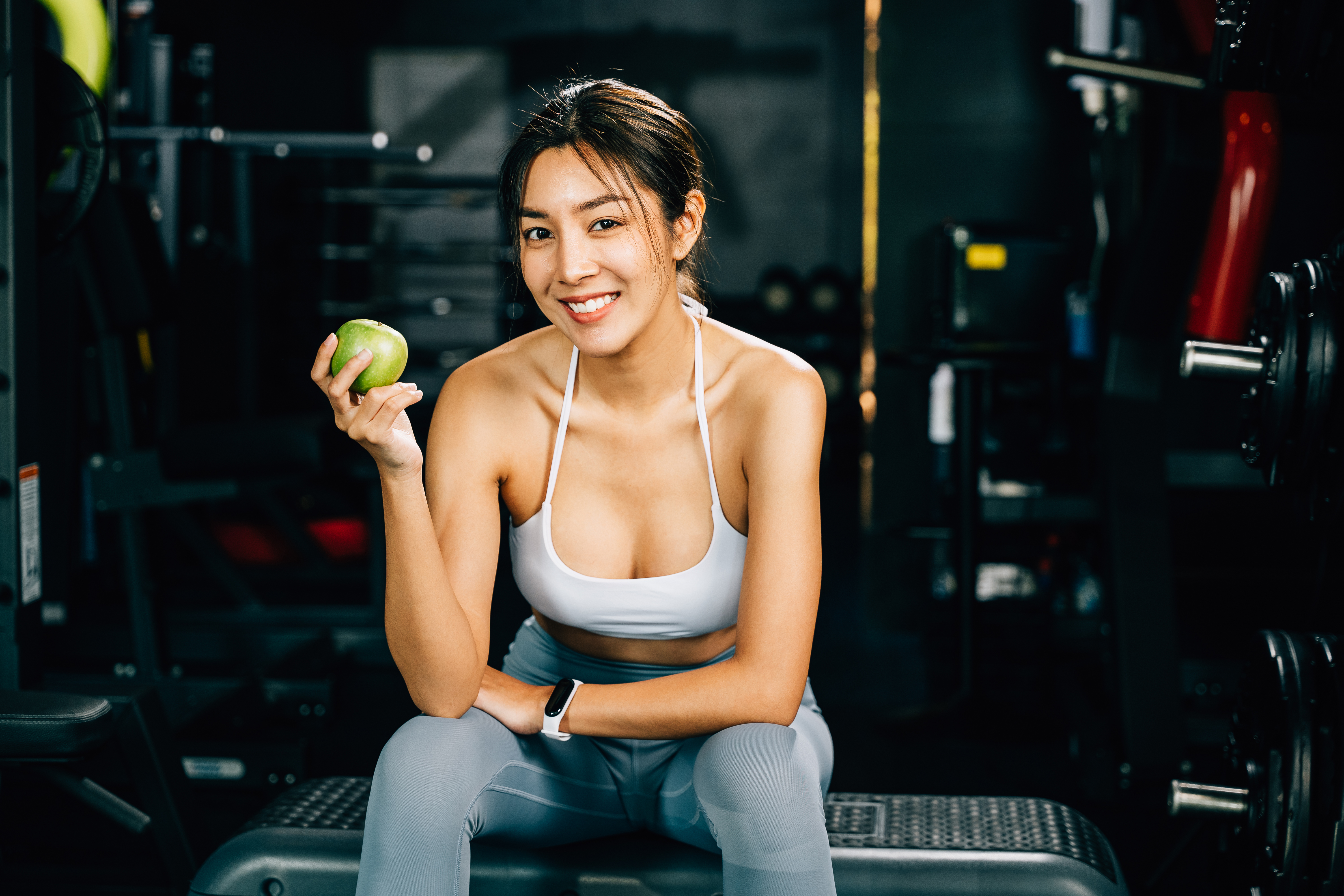 Asian woman holding a green apple in a fitness gym