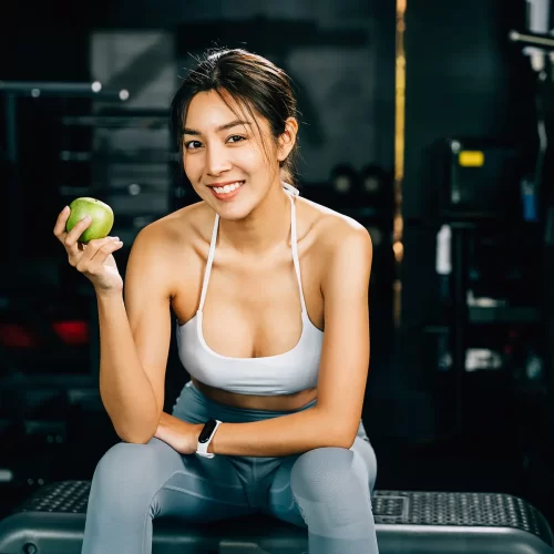 asian-woman-holding-a-green-apple-in-a-fitness-gym
