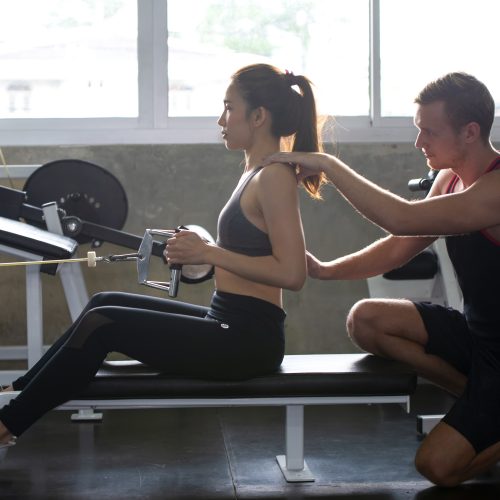 Female exercising with personal trainer at gym