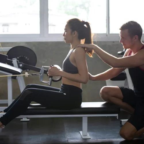 female-exercising-with-personal-trainer-at-gym
