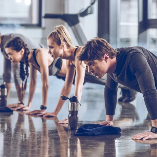 group-of-athletic-young-people-in-sportswear-doing-push-ups-or-plank-at-the-gym-group-fitness